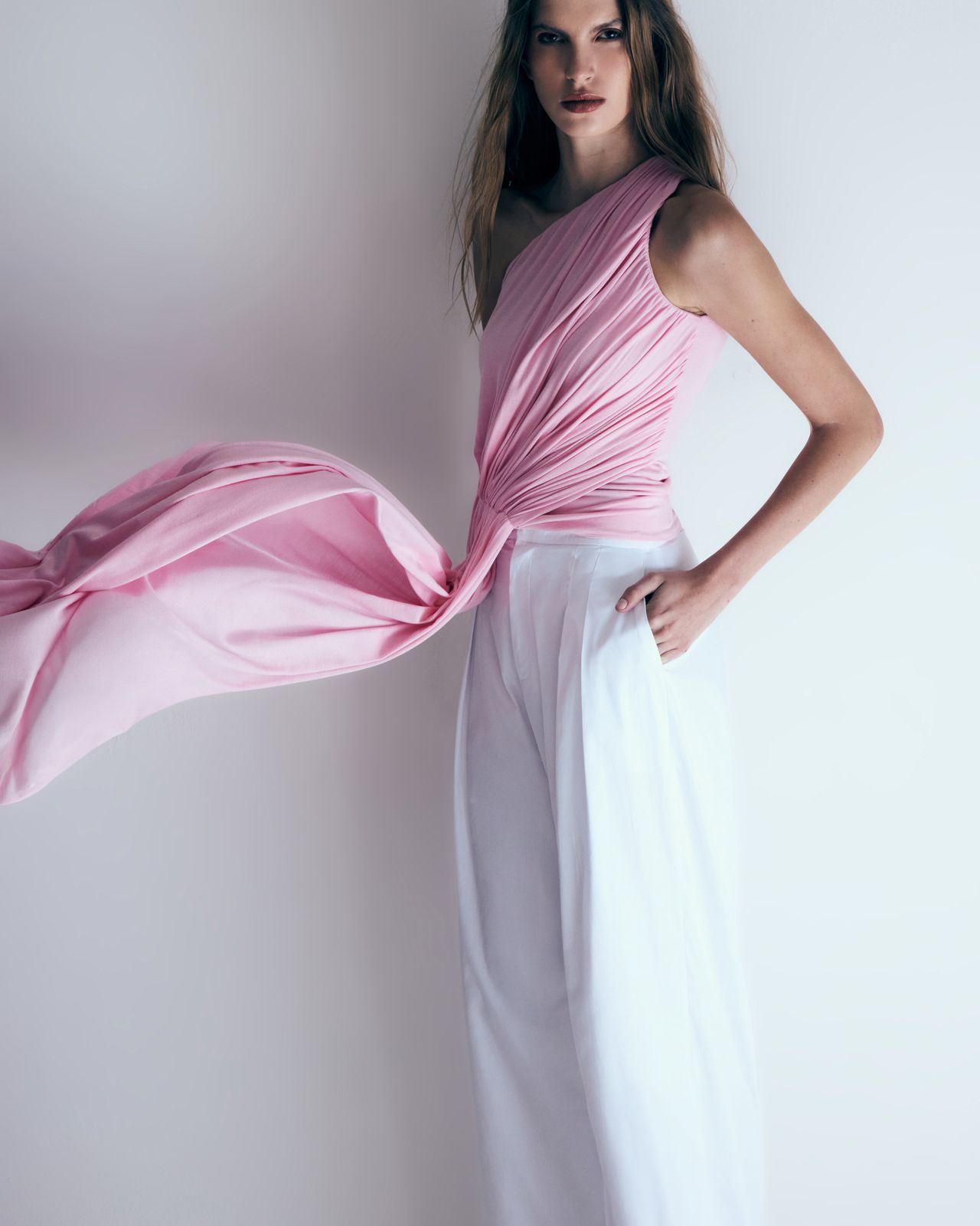 Modelo com blusa drapeada rosa e calça branca